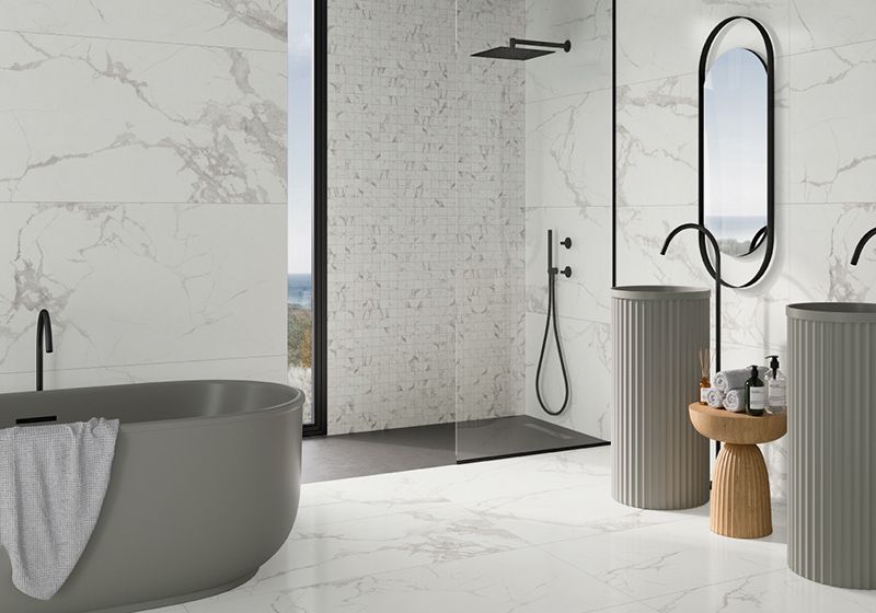 Baño completo con bañera exenta, ducha y dos lavabos altos. Toda la loza en gris y grifería en negro.