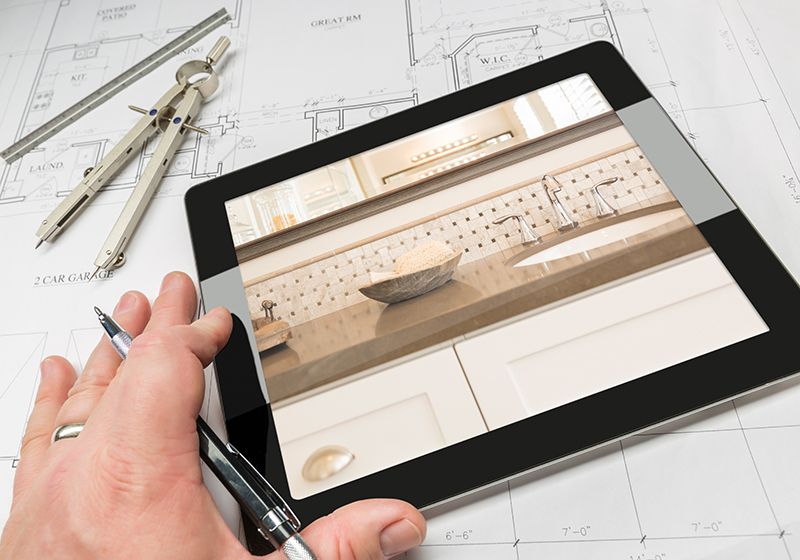 Planos de reforma con un compás encima y una Tablet con el resultado final.